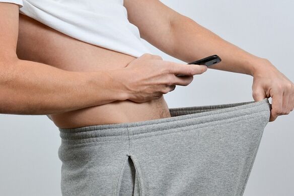 un uomo guarda dall'alto dei pantaloni un pene ingrandito